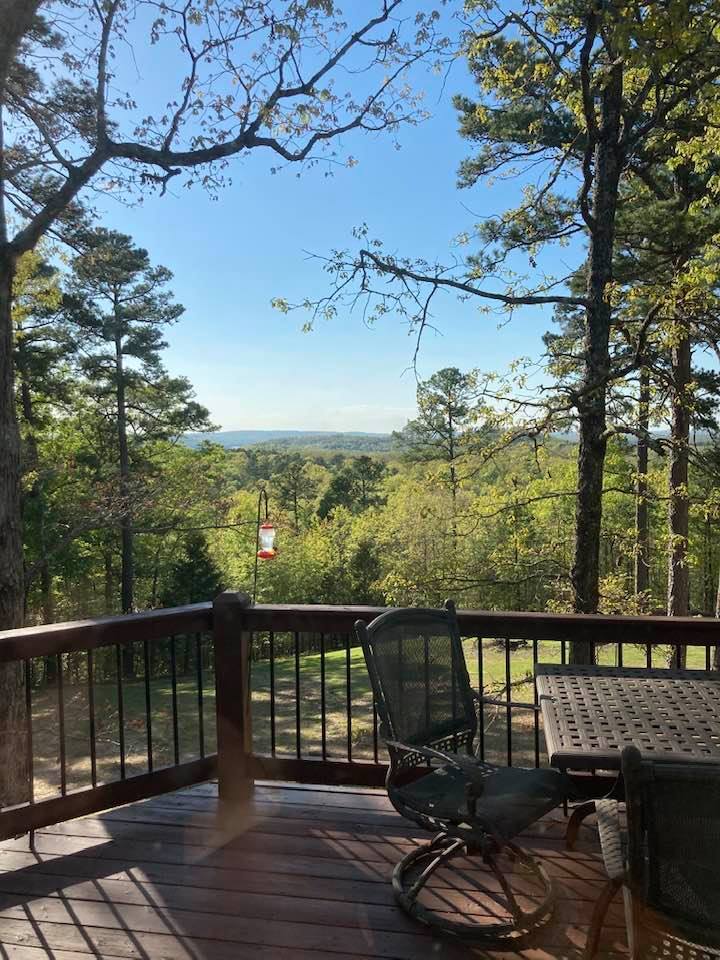 Hummingbird feeder next to a deck with the mountains in the distance