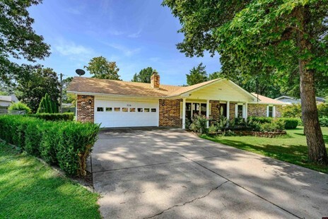 A driveway leading up to a tan and brown brick house.