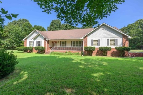 A big yard in front of a brick house.