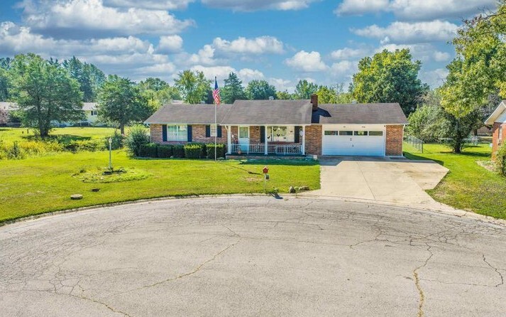 A cul-de-sac with a driveway leading up to a brick house. 